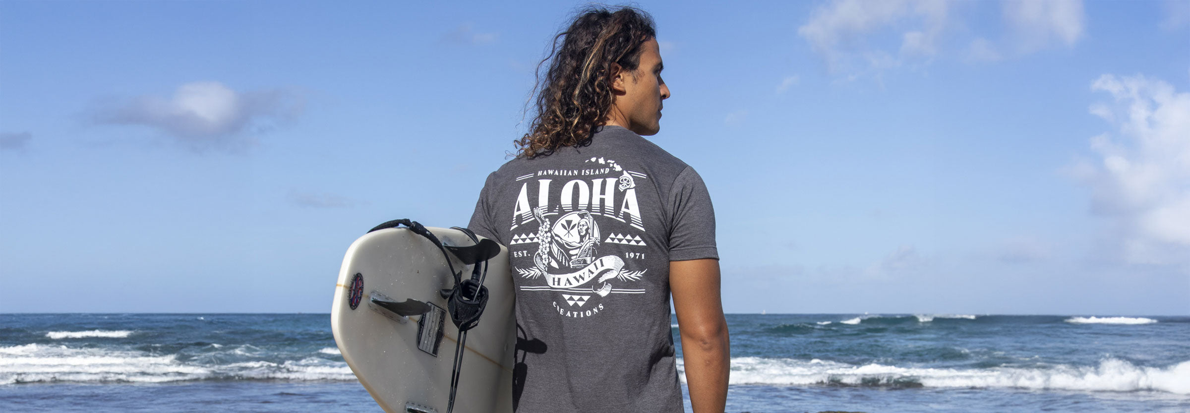 Surfer standing on Hawaii beach inspecting surfboard