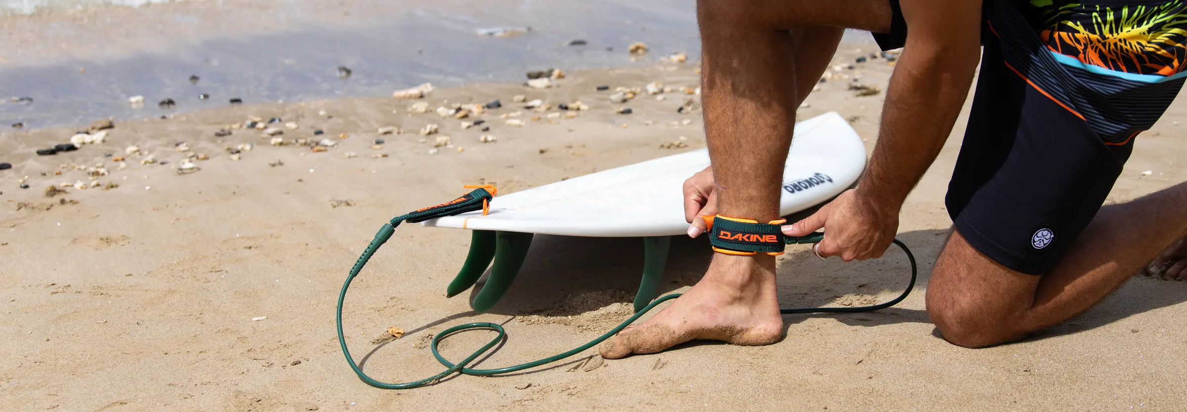 Surfer putting on a Dakine surfboard leash