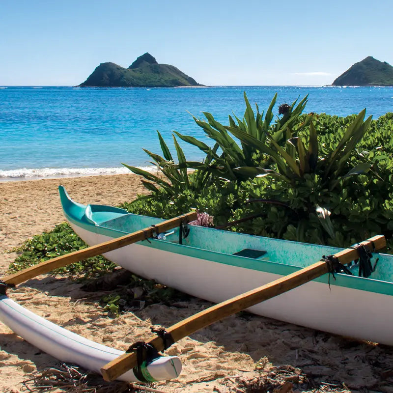 An outrigger canoe sits on Lanikai Beach with the Mokulua Islands in the background