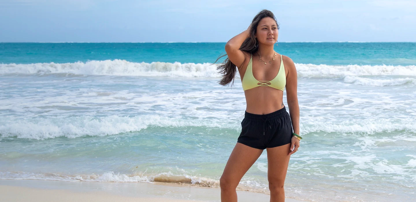 Kalei on the beach in O'Neiil trunks and top.